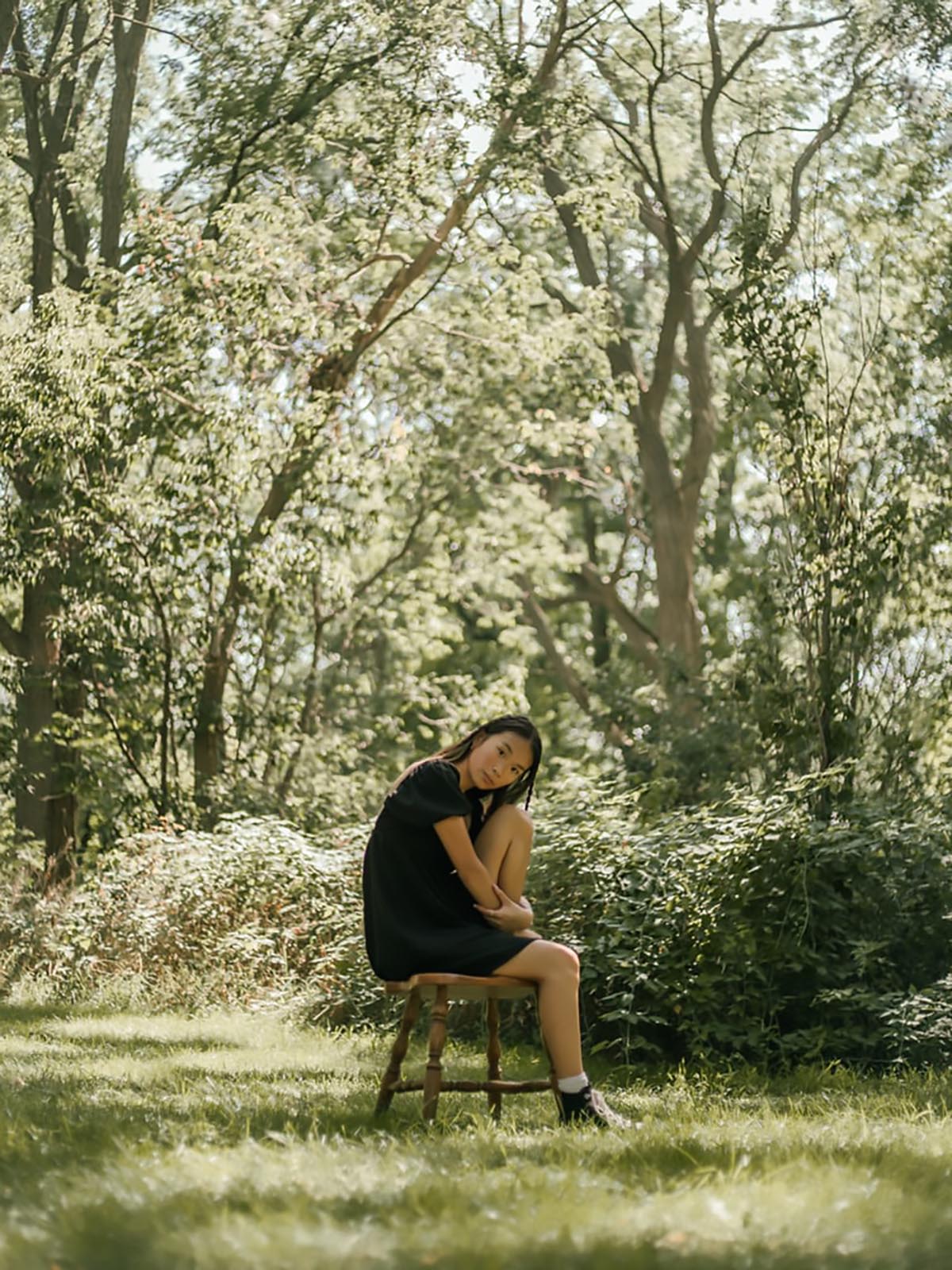 kvinna sitter under ett träd på en stol
